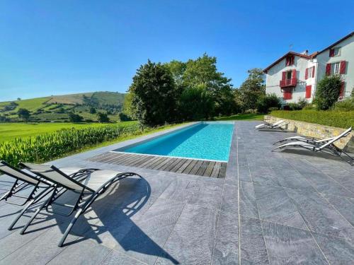 une piscine avec des chaises longues et une maison dans l'établissement Domaine Abartiague, à Ossès