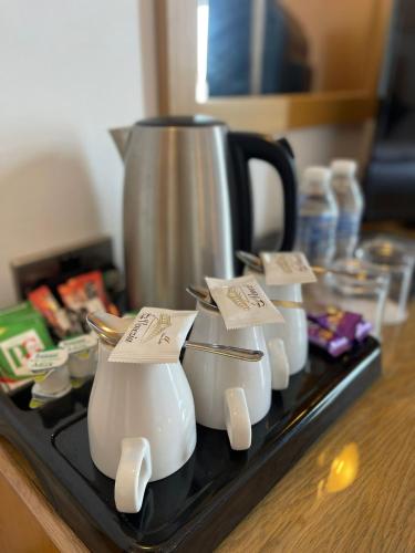 a group of white vases on a counter with a coffee pot at Four Saints Brig Y Don Hotel in Llandudno
