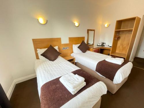 a hotel room with two beds and a mirror at Four Saints Brig Y Don Hotel in Llandudno