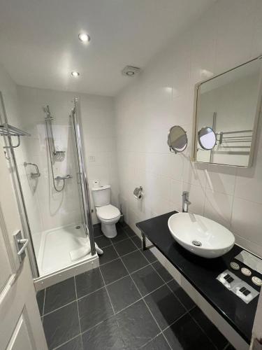 a bathroom with a sink and a shower and a toilet at Four Saints Brig Y Don Hotel in Llandudno