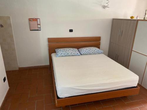 Dormitorio pequeño con cama con sábanas blancas y almohadas azules en Lacro Home, en Rosignano Solvay