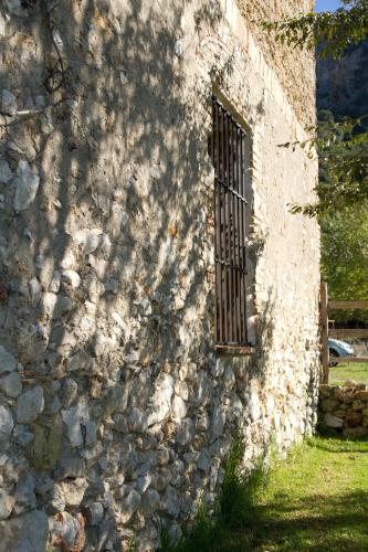 a stone wall with a window with a metal grate at Casa Rural El Vihuelo in El Bosque