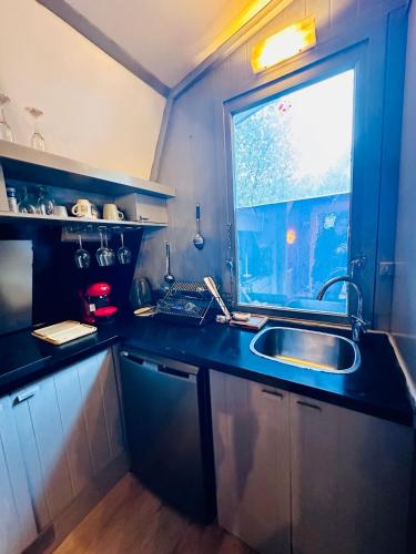 une petite cuisine avec un évier et une fenêtre dans l'établissement Petit chalet à bourg d oisans, à La Paute