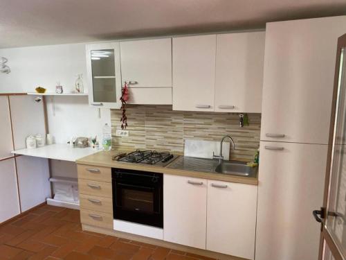 Una cocina con gabinetes blancos, un fregadero y una estufa. en Lacro Home, en Rosignano Solvay