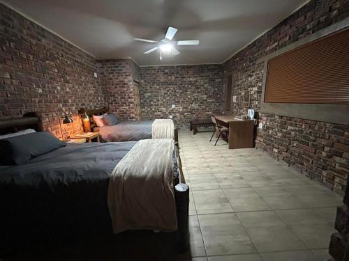 a bedroom with two beds and a brick wall at Sunset Lodge in Kroonstad