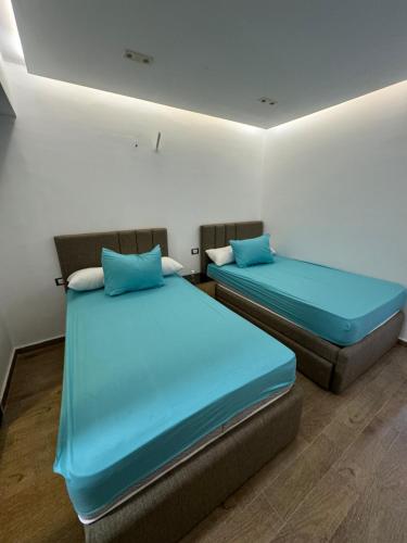 two beds in a room with blue sheets at Helnan portfouad hotel in Chantier Island