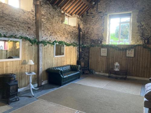 莫尔德Penbedw Uchaf Estate - Rural retreats, tennis的客厅设有真皮沙发,位于石墙内