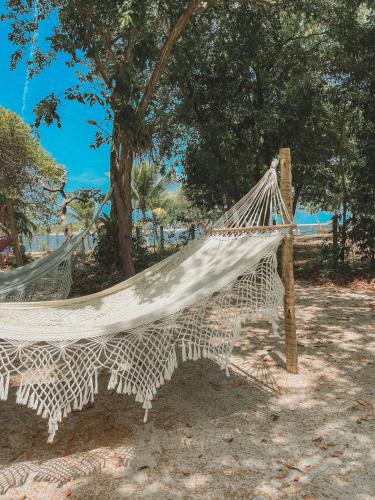 a hammock on the beach near a tree at Pousada Maliale in Ilha de Boipeba