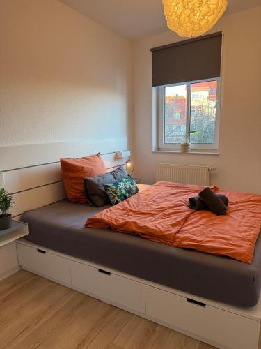 a bedroom with a bed with an orange comforter and a window at Stadt Flair in Eisenach