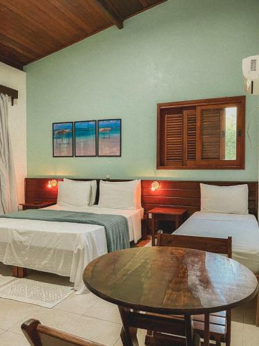 a hotel room with two beds and a table at Pousada Maliale in Ilha de Boipeba