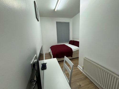 a small white room with a bed and a desk at Sangha Hall in Leicester