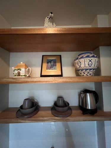 a shelf with pots and vases and a picture at Balay na Bato in Legazpi