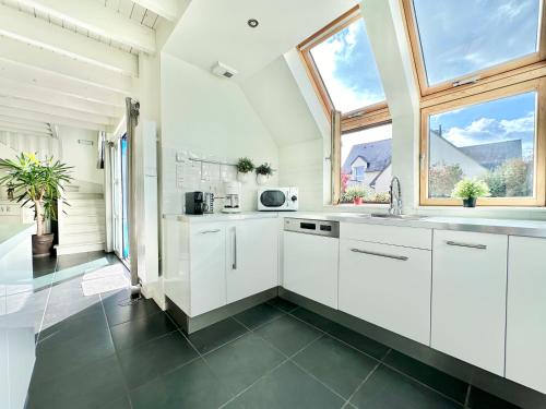 une cuisine avec des placards blancs et une grande fenêtre dans l'établissement Villa BRETAGNE, à Plougrescant