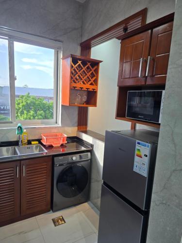 a kitchen with a refrigerator and a sink and a window at Jaxvilla Appartments in Dar es Salaam