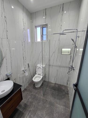 a bathroom with a toilet and a shower and a sink at Jaxvilla Appartments in Dar es Salaam