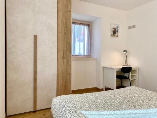 a bedroom with a bed and a desk and a window at Casa di Maggie 1 - Comfort e natura tra Pinzolo e Campiglio in Carisolo
