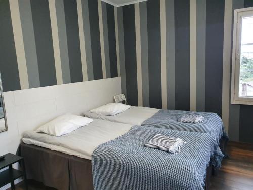 two beds in a room with striped walls at Majatalo Elsa in Hirvihaara