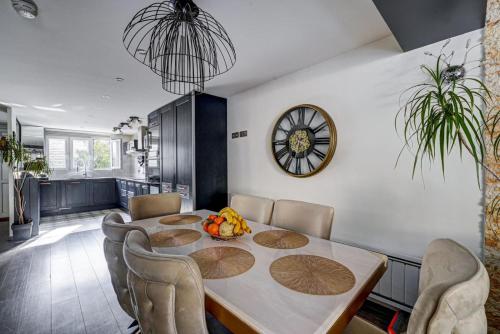 une salle à manger avec une table, des chaises et une horloge dans l'établissement Villa KOSY, à Neuilly-Plaisance