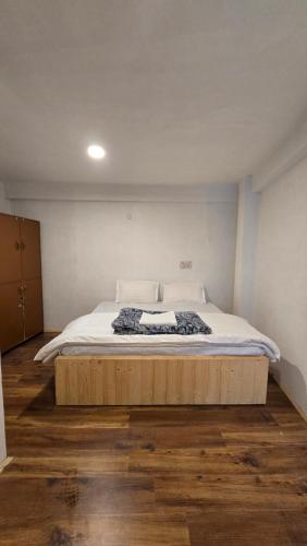 a bedroom with a large bed with a wooden floor at Old Street House and Cafe in Manāli