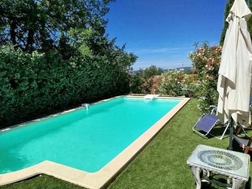 une piscine dans une cour avec un parasol dans l'établissement Roussillon, à Roussillon