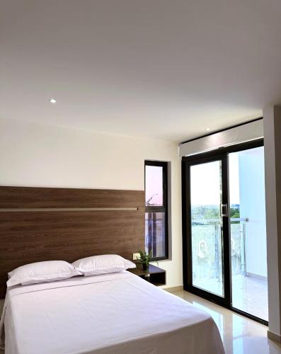 a bedroom with a white bed and a large window at Hotel Duna Real in Uribia
