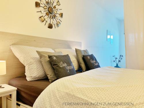 a bedroom with a bed with pillows and a clock at Direkt am Deich! Ferienwohnung de Prigg in Dorum Neufeld