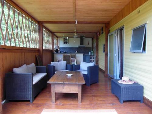 une terrasse couverte avec des canapés et une table ainsi qu'une cuisine dans l'établissement Chalet Alice, à LʼHôpital-Saint-Blaise