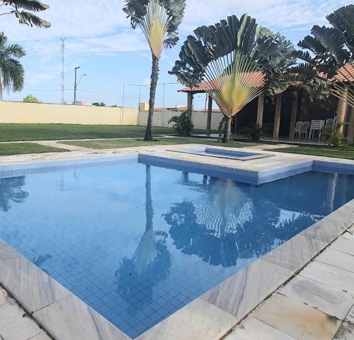 a swimming pool in a yard with palm trees at Accogliente chalet rustico in Maceió