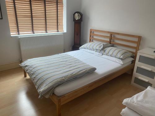a bed in a bedroom with a clock on the wall at Hill Apartments in London