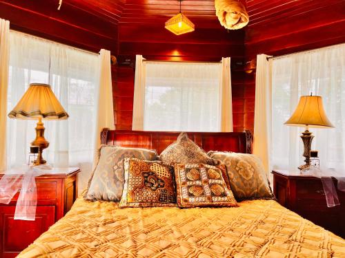 a bedroom with a bed with pillows and windows at Casa Victoriana Aeropuerto in San Juan Arriba