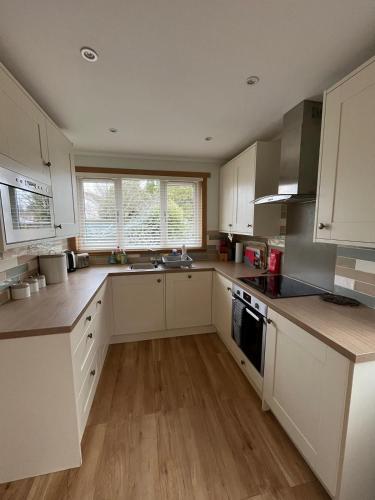 a large kitchen with white cabinets and a sink at Isla Cottage in Blairgowrie