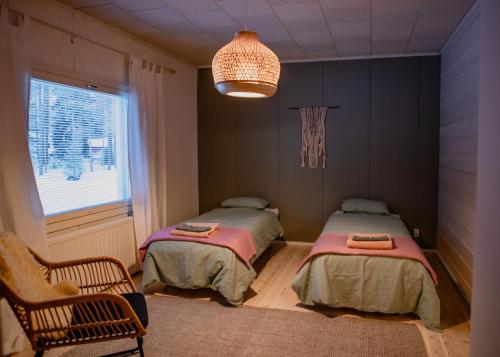 1 Schlafzimmer mit 2 Betten, einem Fenster und einem Kronleuchter in der Unterkunft Talo Mustikankukka Tervola, Finland in Tervola