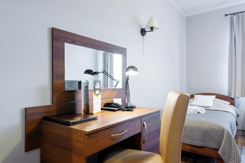 a bedroom with a desk with a mirror and a bed at Hotel Łokietek in Czajowice