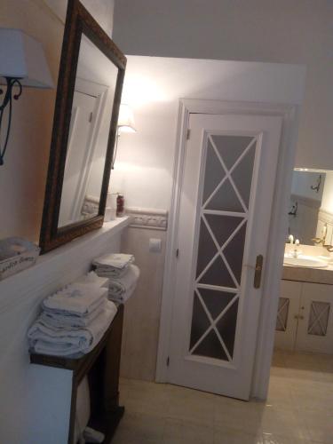 a bathroom with a door and a mirror and towels at Casa de Comedias in Almagro