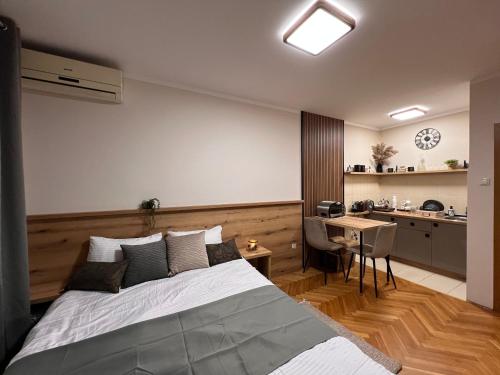 a bedroom with a bed and a desk and a kitchen at Lina Apartment in Podgorica