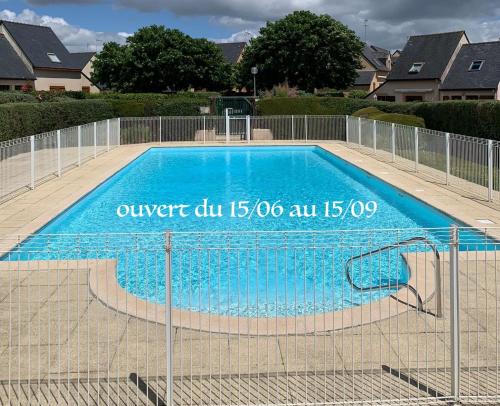 une piscine bleue entourée d'une clôture dans l'établissement Perle Beach, Petite maison située en bord de plage, piscine., à Guidel
