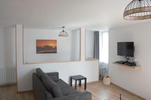 un salon avec un canapé et une télévision dans l'établissement Au coin de la rue, à Vatan