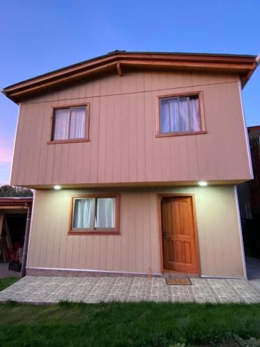 a house with a brown door and three windows at Hospedaje entre Volcanes y Araucarias in Curacautín