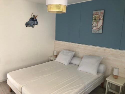 une chambre avec un lit blanc avec un mur bleu dans l'établissement Charmante maisonette, à Soustons