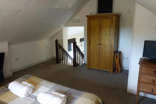 a room with a bed and a tv and a staircase at Home Farm & Lodge in Bawtry