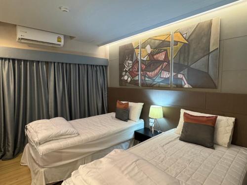 a hotel room with two beds and a painting on the wall at Cha-am , Cityscape Comfort , Near Cha-am Beach South in Cha Am