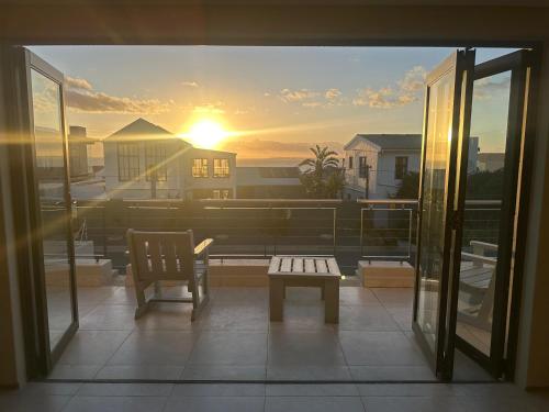 a view of a balcony with a bench and the sunset at Blouberg Village Place in Cape Town