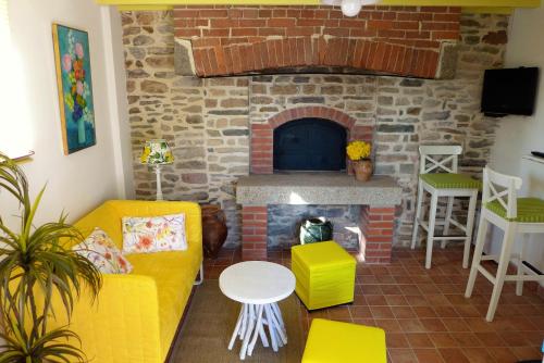Elle comprend un salon doté d'une cheminée en briques et d'un mobilier jaune. dans l'établissement La Boulangerie, à Genêts