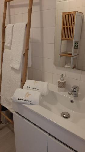 a bathroom with a white sink with towels on it at Não te vou esquecer Aldeia da Luz! in Luz