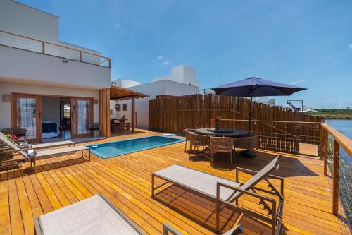 a deck with a pool and a table with an umbrella at Bahia Soul - Casa Ayla - Barra Grande - Península de Maraú in Marau