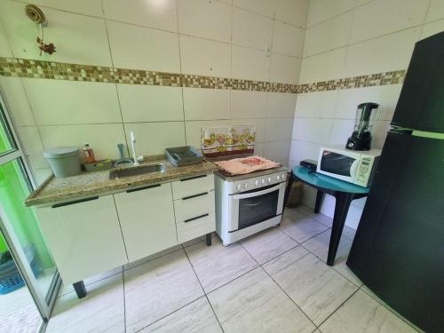 a small kitchen with a stove and a microwave at Casa Sophia9 in Três Lagoas