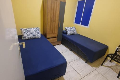 a room with two beds and a chair and a window at Casa Sophia9 in Três Lagoas