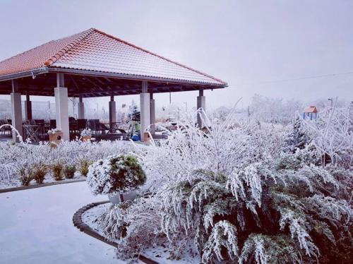 a garden covered in snow with a gazebo at Hotel Łokietek in Czajowice