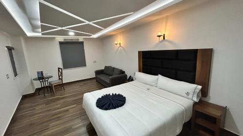 a bedroom with a large white bed and a chair at Hotel ANB Aeropuerto Guadalajara in Guadalajara