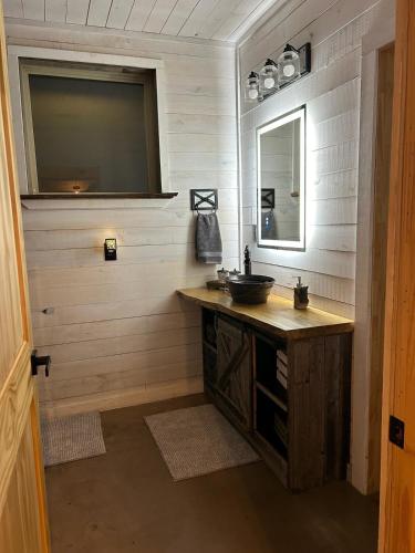 a bathroom with a sink and a mirror at The Knotty Pine Cabin at Cabins of Wolf Pen Gap in Mena